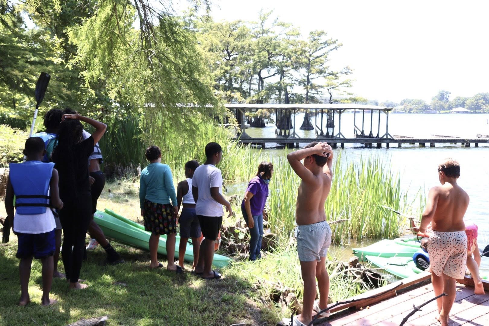 A group of adults and children standing by a lake.